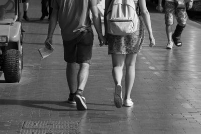 Low section of friends walking on street