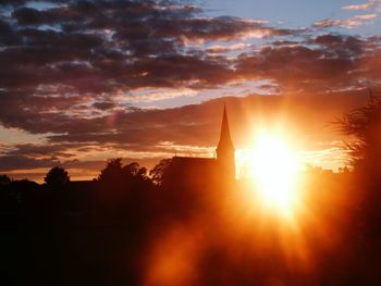 Silhouette church against cloudy sky during sunset