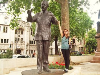 Woman standing by statue against trees