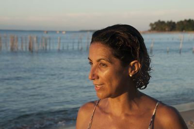 Close-up of smiling woman looking away while standing at beach