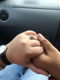 Midsection of couple holding hands in car