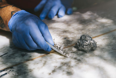 Closeup of gloved hands removing old wax with a wax comb. person