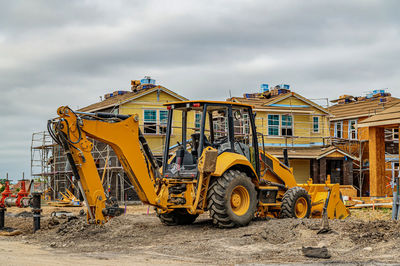 Excavator at construction site. frame houses with sip panels in background.