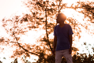 Low angle view of man standing on tree against sky