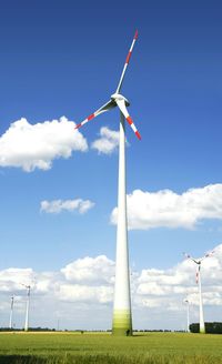 Wind turbines on field against blue sky