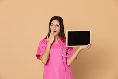 Portrait of woman standing against pink background