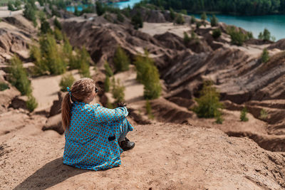 Rear view of woman sitting on sand at sand quarry