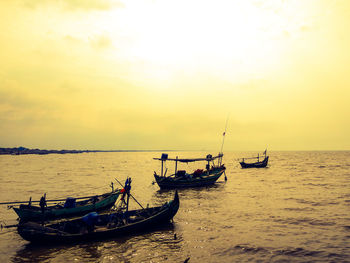 Boats moored in sea against sky during sunset