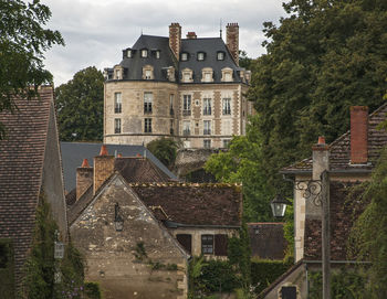 Houses by castle in town against sky