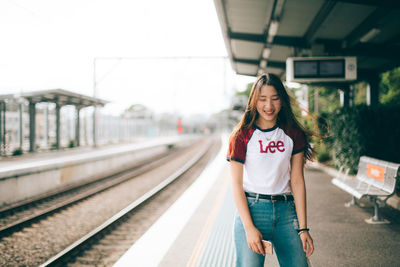 Portrait of smiling woman standing at railroad station