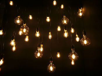 Low angle view of electric bulbs hanging in darkroom