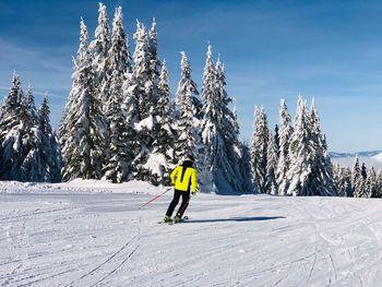 Rear view of man skiing on snow covered mountain against sky