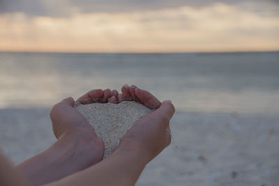 Midsection of person on beach against sky