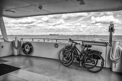 Bicycle by sea against sky