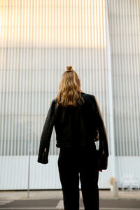 Rear view of woman with umbrella walking in city