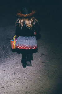 Rear view of girl walking on road at night
