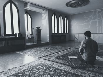 Rear view of woman sitting in front of wall