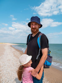 Happy family father daughter hugging on marine landscape. bearded dad and child  having fun together