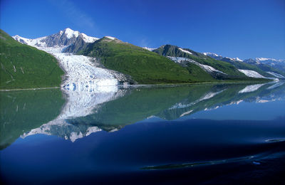 Scenic view of lake and mountains against blue sky