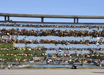 Love locks on bridge over river against sky