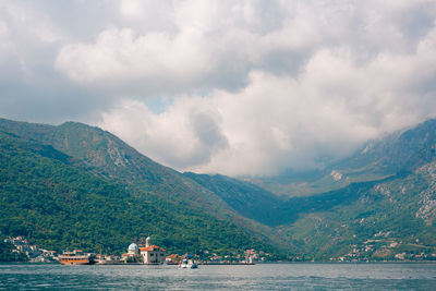 Scenic view of sea by mountains against sky