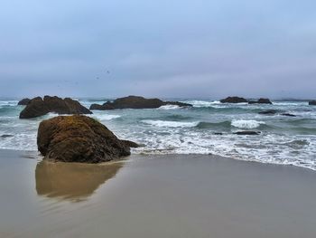 Scenic view of rocks on beach against sky