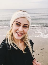 Portrait of smiling young woman standing at beach