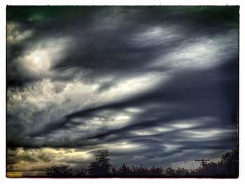 Silhouette of trees against cloudy sky