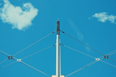 Low angle view of cables connected on pole against blue sky