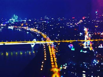 Illuminated bridge over river in city at night