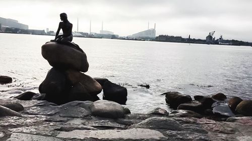Statue on rock in sea