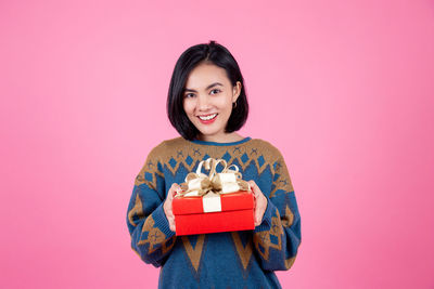 Portrait of a smiling young woman against pink background