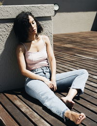 Mid adult woman sitting by wall