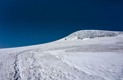 Low angle view of snowcapped mountain against clear blue sky