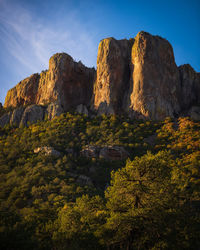 Rock formation by tree against sky