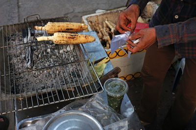 A close-up of  hand preparing to use a nylon bag to wrap a plastic cup of scallion oil 