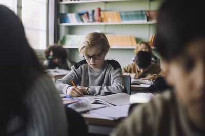 Pupil writing in book during exam in classroom