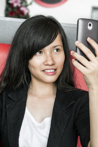 Portrait of smiling young woman using mobile phone