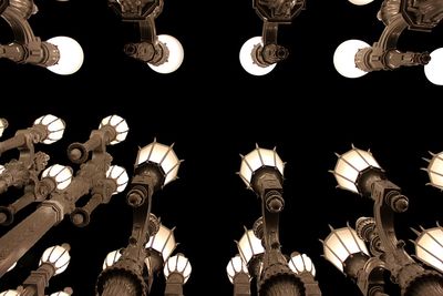 Low angle view of illuminated light bulbs hanging at night