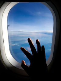 Close-up of hand through airplane window