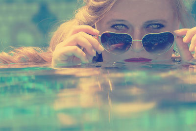 Close-up portrait of woman with sunglasses swimming in water