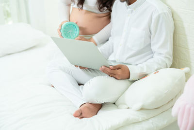 Midsection of woman relaxing on bed at home