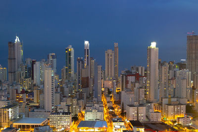 Illuminated modern buildings in city against sky