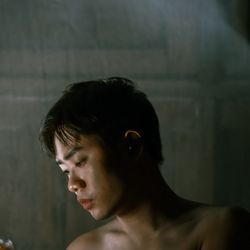 Portrait of young man looking away against wall