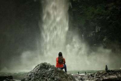 Rear view of man looking at waterfall