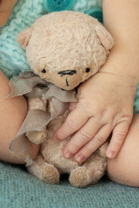 Vertical. newborn baby hand with hand-made teddy bear on a turquoise background