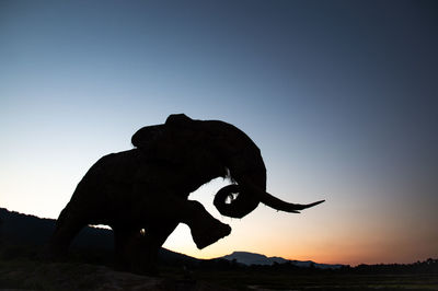 Low angle view of silhouette statue against clear sky