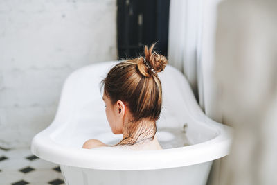 Young happy woman taking bath with foam at home, treat yourself