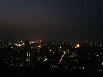 Illuminated cityscape against sky at night