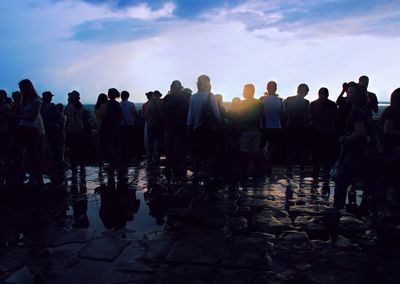 Group of people standing on shore against sky